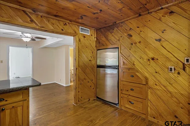 a view of a refrigerator in kitchen and an empty room