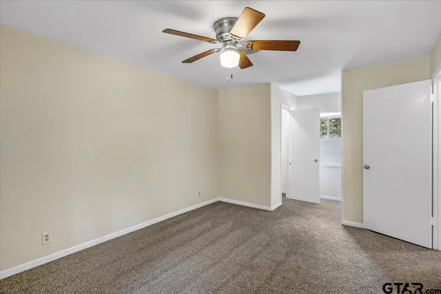 an empty room with closet and a ceiling fan