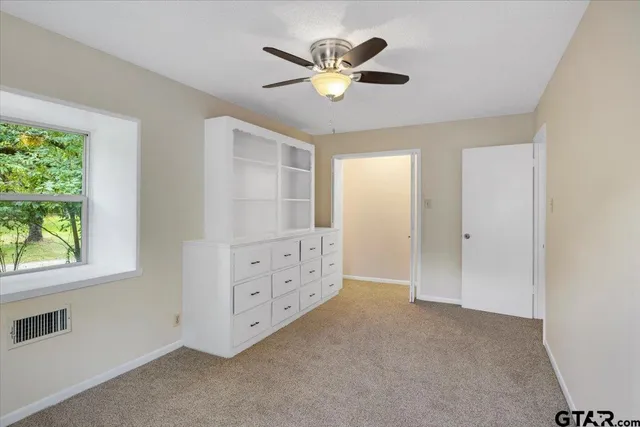 an empty room with a ceiling fan and a window