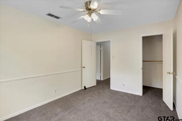 an empty room with windows and chandelier fan