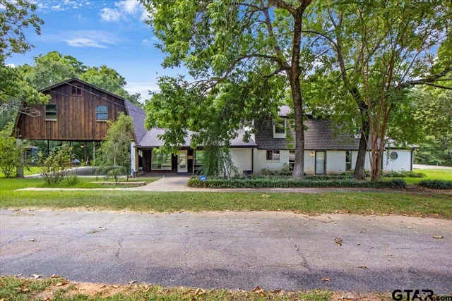 a view of a big house next to a yard with big trees