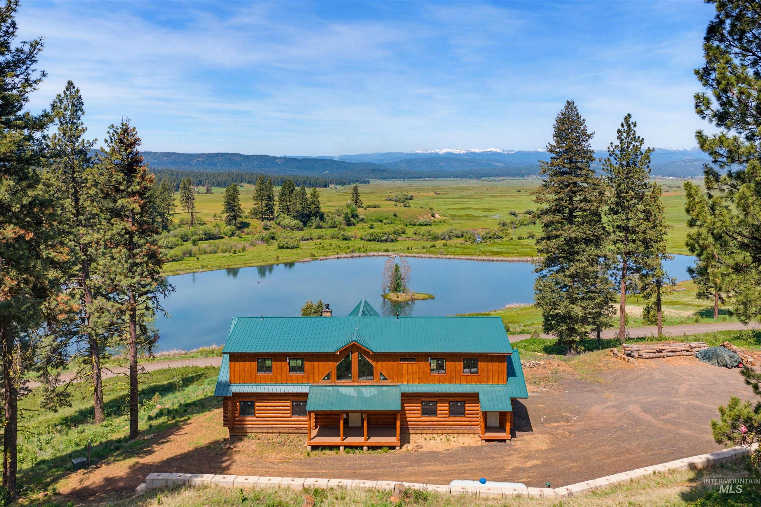 3322 Big Creek Road New Meadows, ID 83654 - Photo 4 of 50 Log home exterior featuring a teal-colored metal roof, visible log construction, and multiple windows