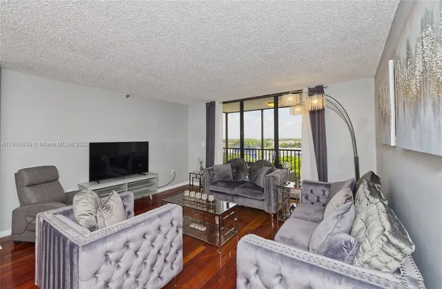 a living room with furniture a flat screen tv and a floor to ceiling window