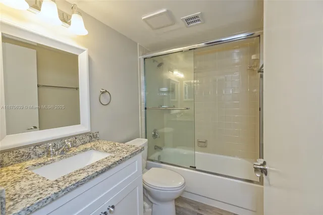 a bathroom with a granite countertop sink toilet and shower