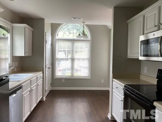 a kitchen with stainless steel appliances a stove cabinets and wooden floor