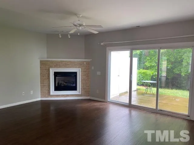 a view of an empty room with wooden floor and a fireplace