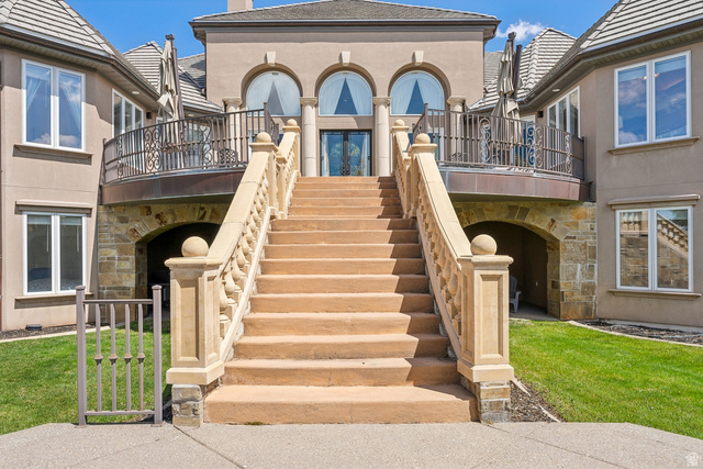 1714 Ridge Point Drive Bountiful, UT 84010 - Photo 98 of 132 Grand exterior staircase with stone balustrades, wrought iron balcony, arched windows, and a stone archway