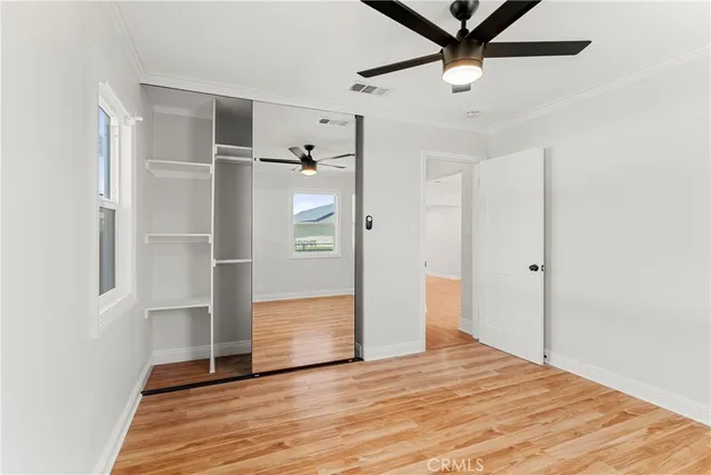 a view of empty room with wooden floor and ceiling fan