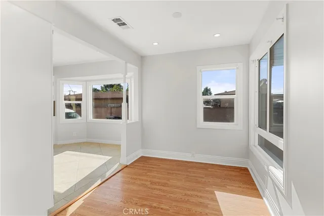 a view of an empty room with a window and wooden floor
