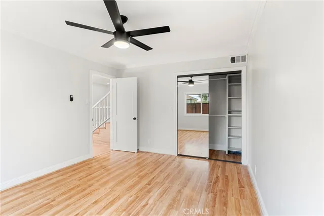 a view of empty room with wooden floor and fan