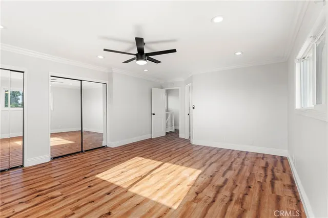 a view of empty room with wooden floor and fan