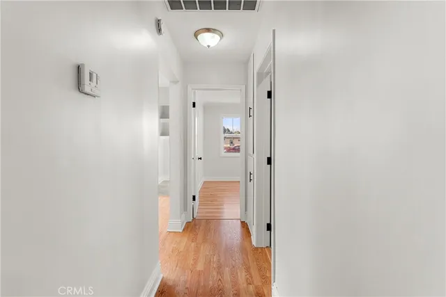 a view of a hallway with wooden floor and a bathroom