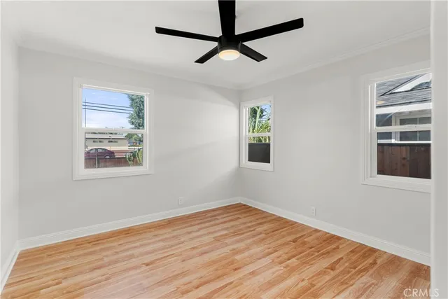 a view of empty room with wooden floor and fan