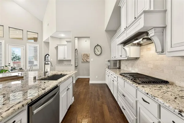 a large kitchen with stainless steel appliances granite countertop a lot of counter space and wooden floors