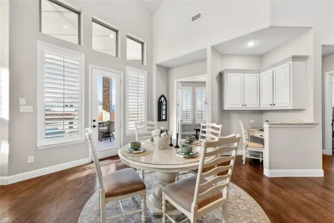 a dining room with wooden floor and large windows