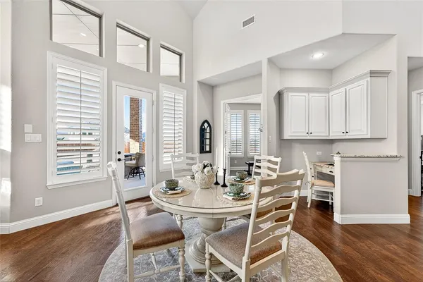 a dining room with wooden floor and large windows