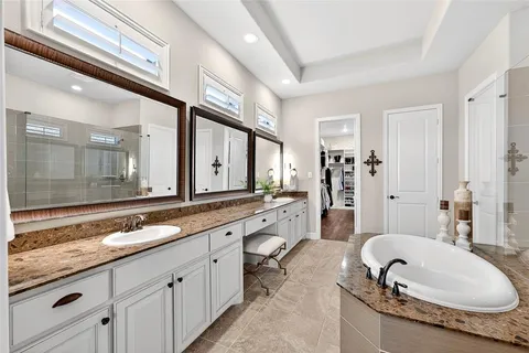 a large bathroom with a granite countertop double vanity sink a mirror and a bathtub