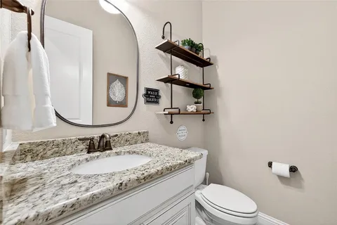 a bathroom with a granite countertop sink a toilet and a mirror