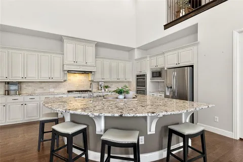 a kitchen with stainless steel appliances granite countertop a table chairs sink refrigerator and cabinets