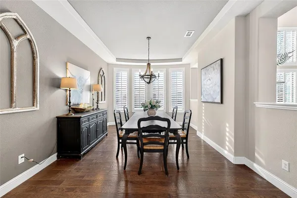 a dining room with wooden floor a chandelier a wooden table and chairs