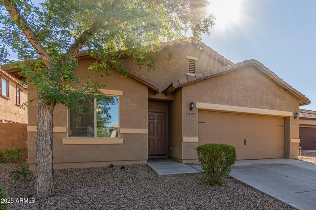 a view of a small house with a yard plants and large tree