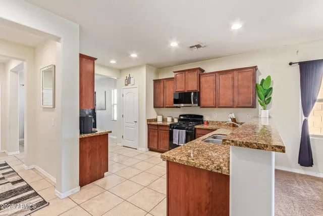 a kitchen with stainless steel appliances granite countertop a stove top oven a sink a refrigerator and a granite counter tops