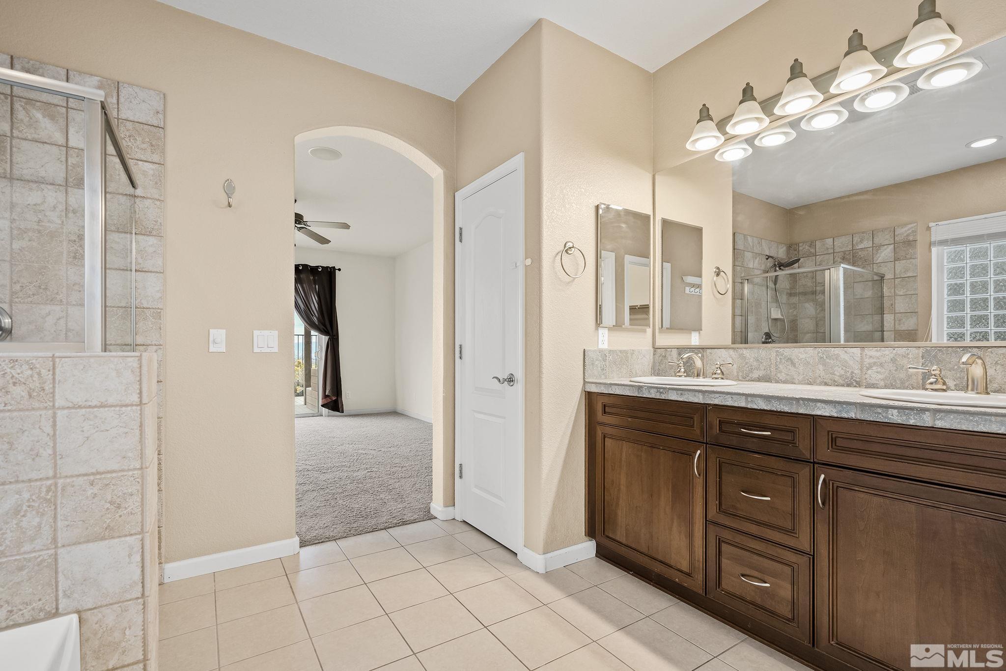 7144 Crest Hill Drive Reno, NV 89506 - Photo 17 of 28 a spacious bathroom with a granite countertop sink a mirror and a shower