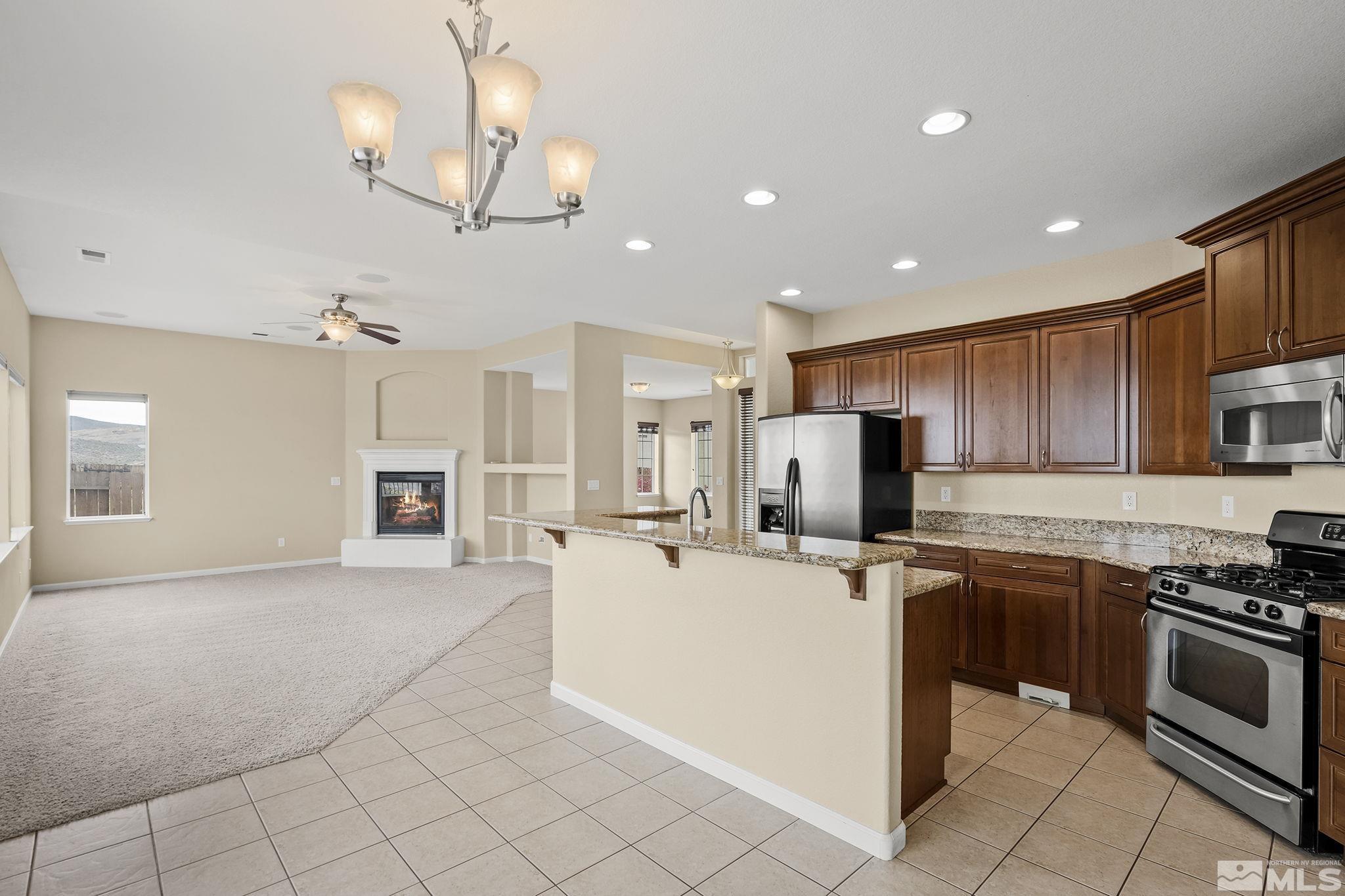 7144 Crest Hill Drive Reno, NV 89506 - Photo 7 of 28 a kitchen with stainless steel appliances kitchen island granite countertop a sink and cabinets
