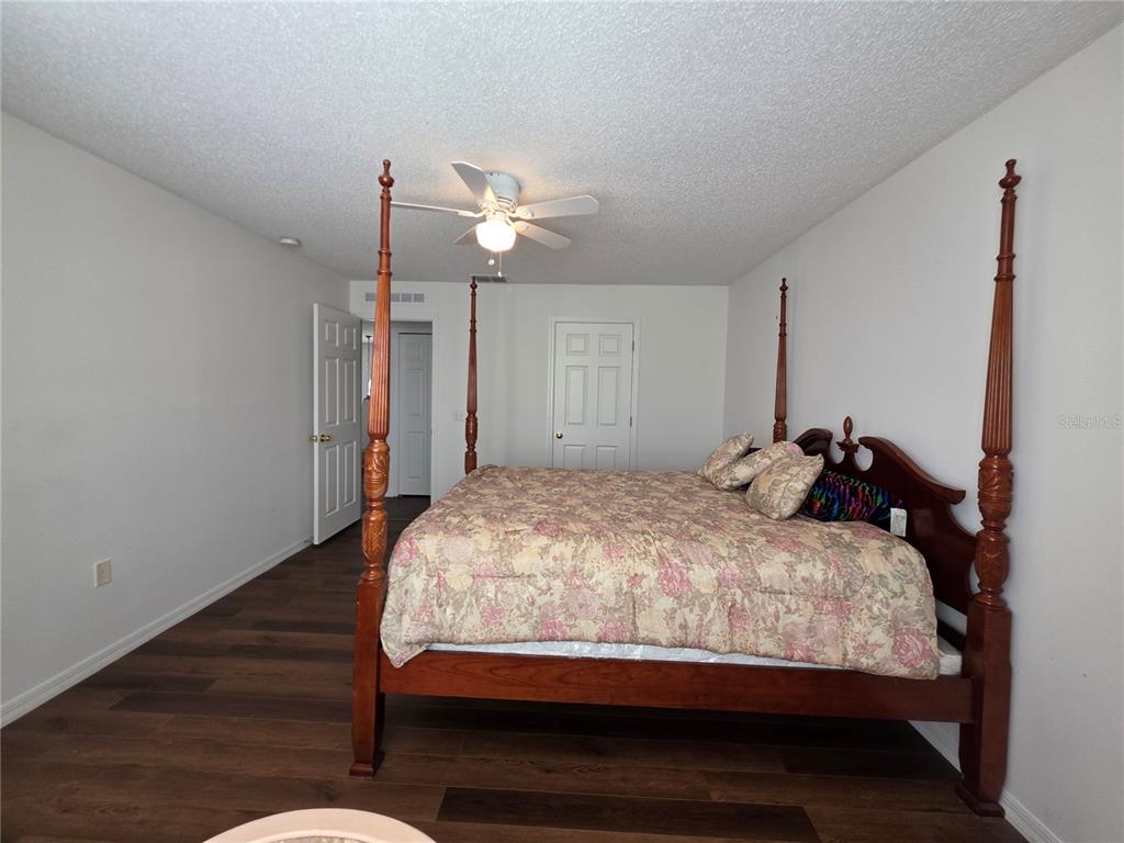 9276 Elm Court Spring Hill, FL 34606 - Photo 17 of 35 a bedroom with a bed ceiling fan and a wooden floor