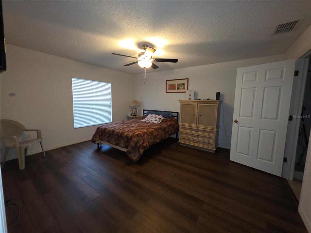 9276 Elm Court Spring Hill, FL 34606 - Photo 10 of 35 a bedroom with a bed and a chandelier