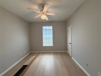 an empty room with wooden floor fan and windows