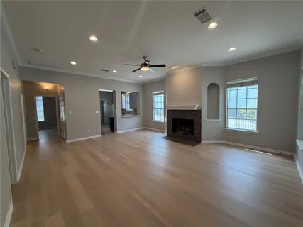 an empty room with wooden floor fireplace and windows