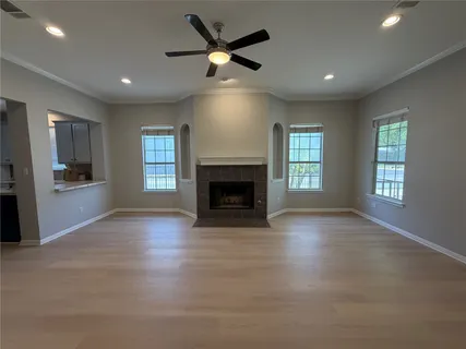 an empty room with windows fireplace and a kitchen view