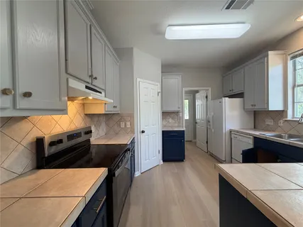a kitchen with stainless steel appliances kitchen island granite countertop a stove refrigerator and cabinets
