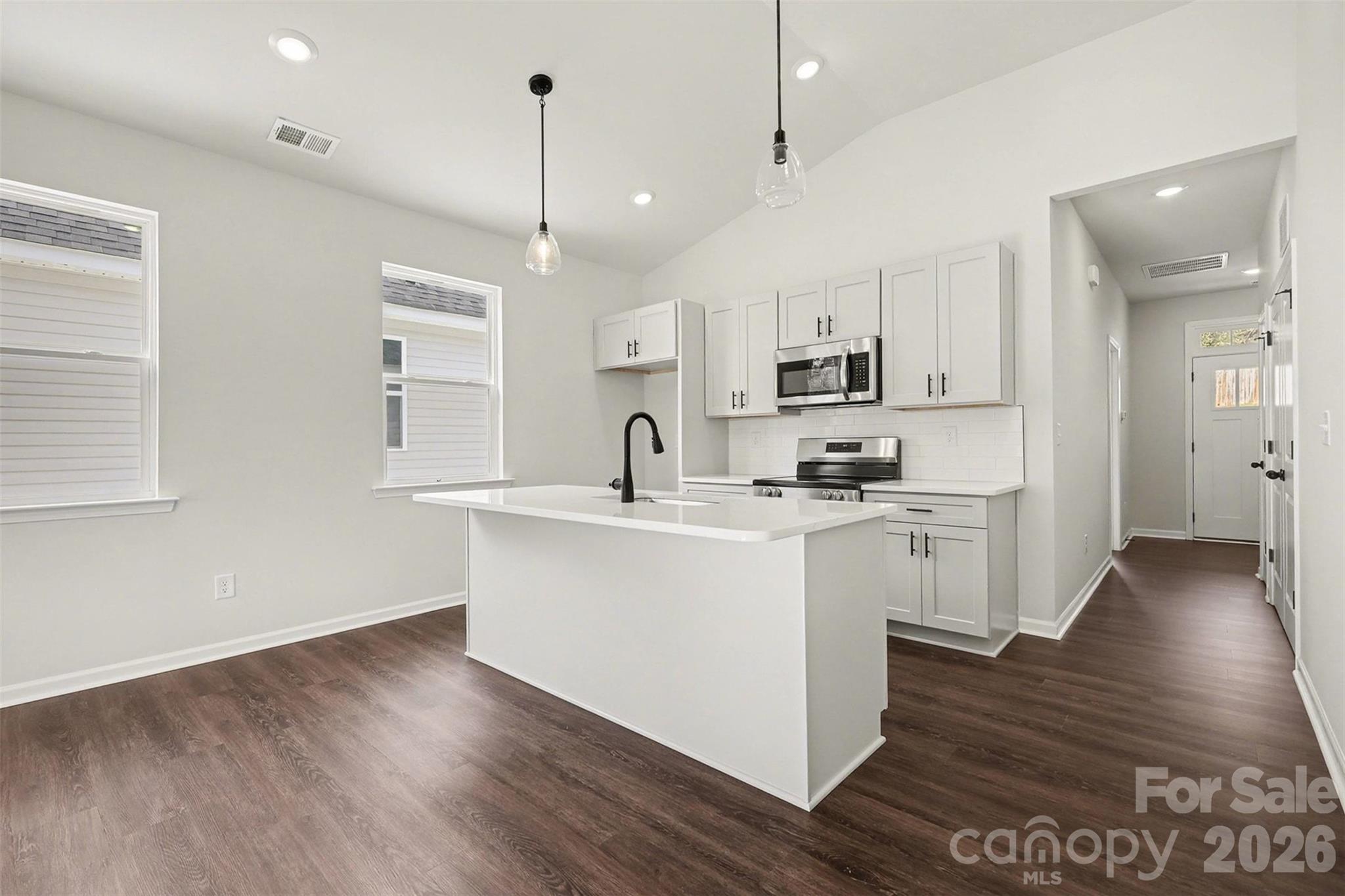 508 Mill Street Lowell, NC 28098 - Photo 5 of 27 a kitchen with stainless steel appliances granite countertop a sink a stove a refrigerator and white cabinets with wooden floor