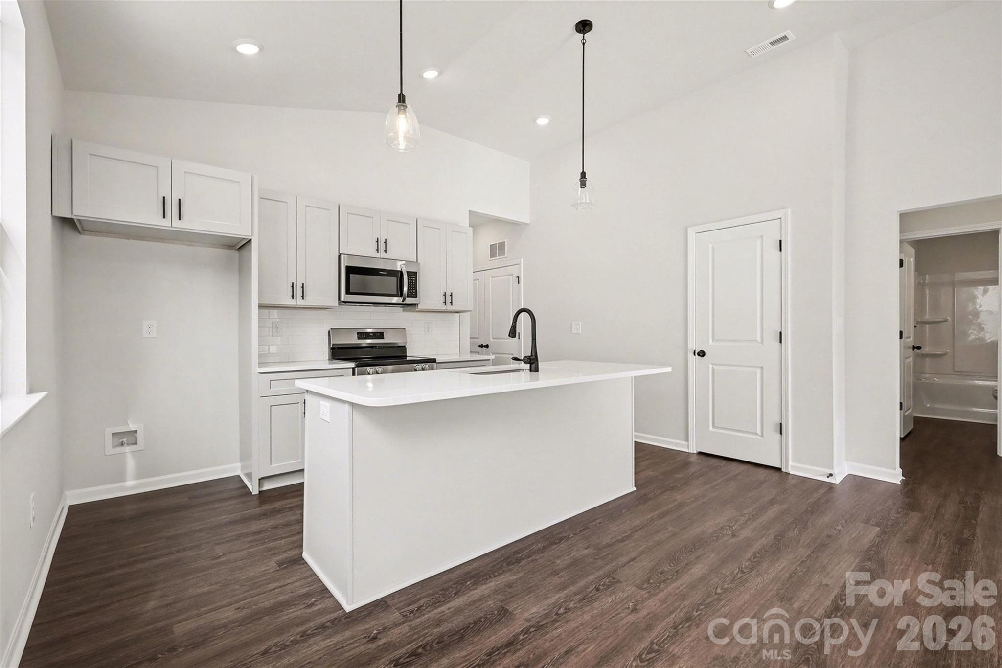 508 Mill Street Lowell, NC 28098 - Photo 9 of 27 a kitchen with stainless steel appliances granite countertop a sink a stove a refrigerator and white cabinets with wooden floor