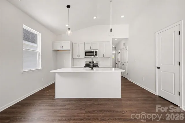 a view of kitchen with stainless steel appliances sink large window and wooden floor