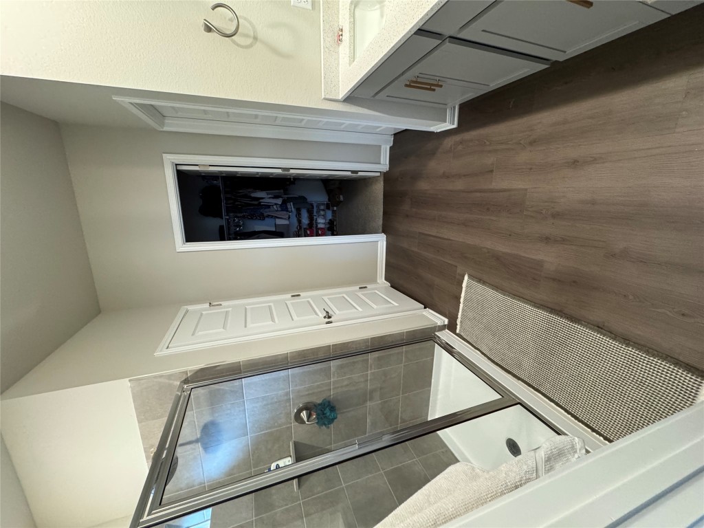 Full bathroom with vanity, a walk in closet, a stall shower, and dark wood finished floors