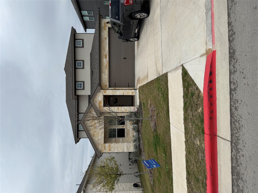 429 El Capitan Loop Dripping Springs, TX 78620 - Photo 18 of 18 Exterior of house featuring a driveway, garage, and grassy front yard