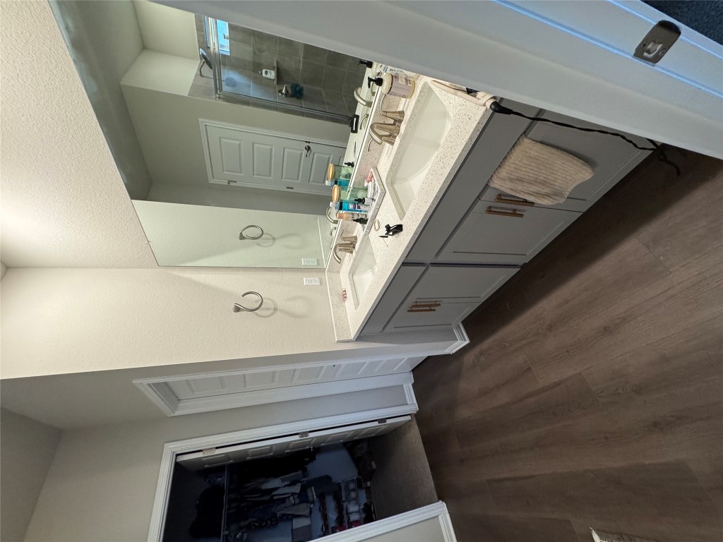 429 El Capitan Loop Dripping Springs, TX 78620 - Photo 2 of 18 Full bathroom with vanity, a walk in closet, a stall shower, and dark wood finished floors