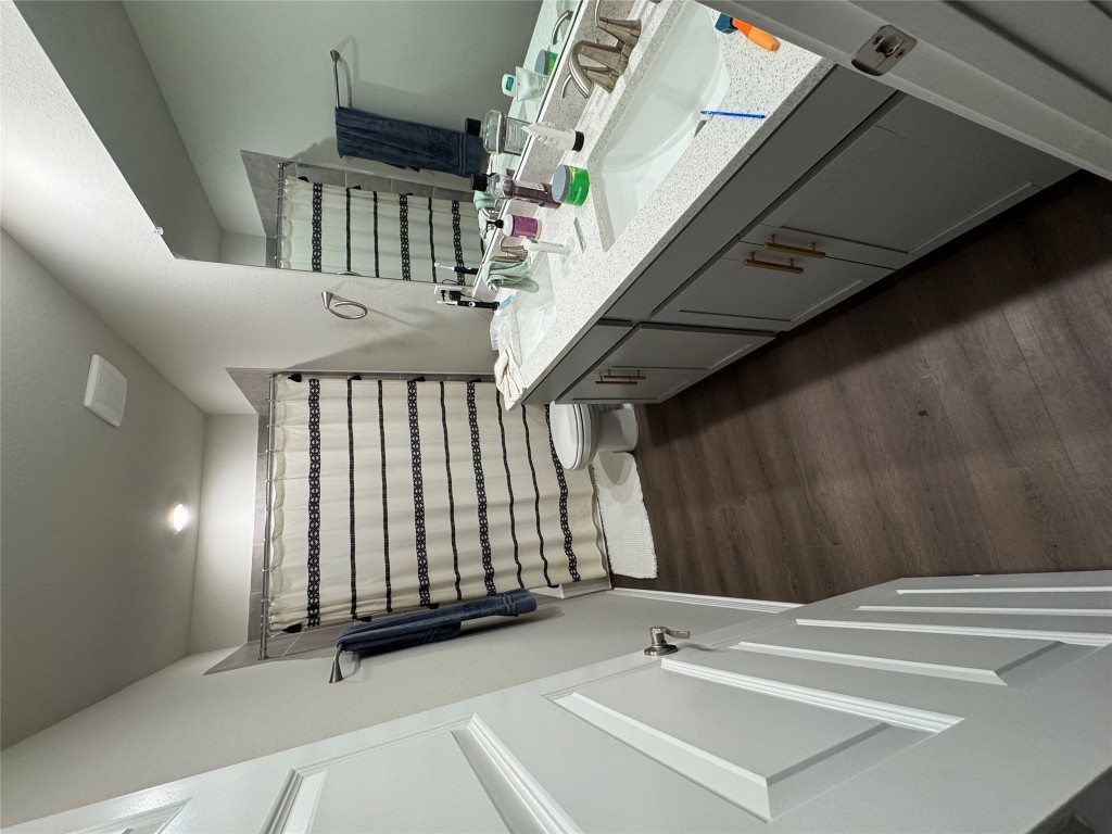 429 El Capitan Loop Dripping Springs, TX 78620 - Photo 3 of 18 Full bathroom with vanity, a walk in closet, a stall shower, and dark wood finished floors
