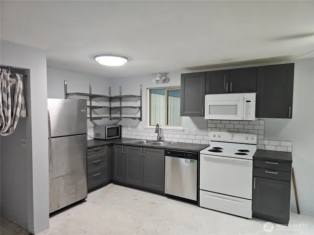 a kitchen with stainless steel appliances granite countertop white cabinets a refrigerator a sink a stove a microwave and island