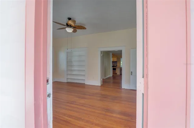 wooden floor in an empty room with a fireplace and a window