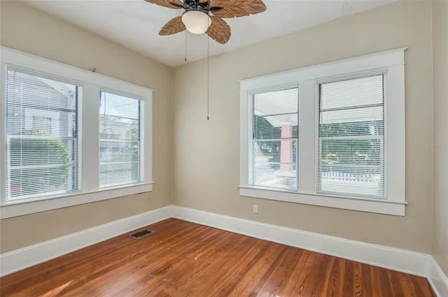 a view of an empty room with wooden floor and a window