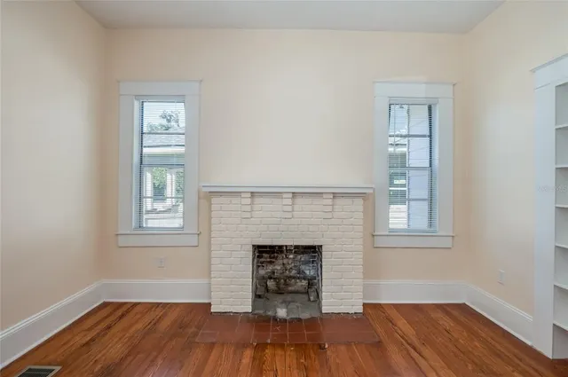 a view of a livingroom with a fireplace wooden floor and window