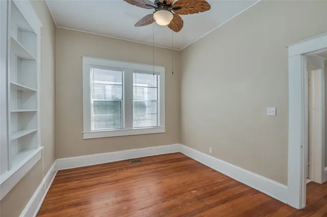 an empty room with wooden floor cabinet and windows