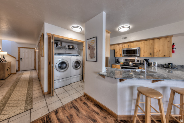 3461 Westwater Road, Unit 6 Moab, UT 84532 - Photo 12 of 33 Kitchen featuring a breakfast bar, washing machine and dryer, light wood-style flooring, stainless steel appliances, and a peninsula