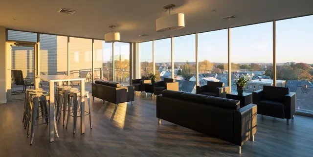 a living room with furniture large windows and wooden floor
