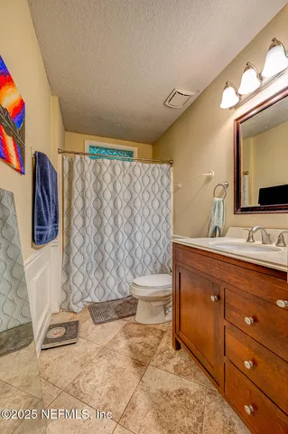 a bathroom with a granite countertop toilet sink and mirror