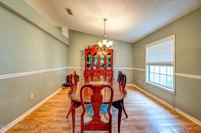 a dining room with furniture a chandelier and wooden floor